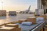 مشهد تصوري لشحنات بريدية على سير مناولة في منشأة شحن جوي غير محددة